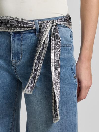 Frauenmodel trägt Wide Fit Jeans mit Viskose-Anteil Modell 'Palazzo' von Buena Vista, mittleres Jeansblau, Paisley-Stoffband, Nahaufnahme Oberkörper. Elastischer Baumwoll-Mix, 5-Pocket-Design, verkürzte Passform, Knopf-Rißverschluss.