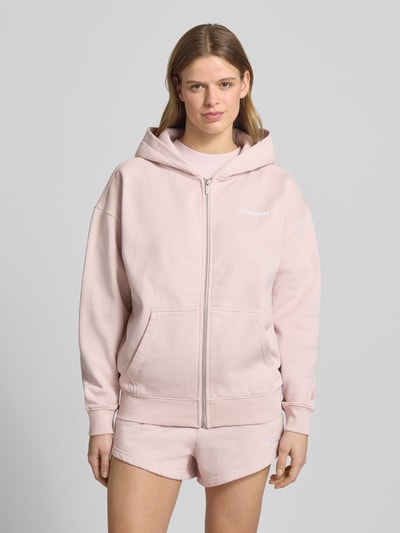 Frauenmodel trägt Oversized Sweatjacke mit Label-Stitching Modell 'CLARITA' von Pegador in Rosa, Baumwoll-Mix, Känguru-Tasche, Reißverschluss, Ganzkörperansicht von vorne.