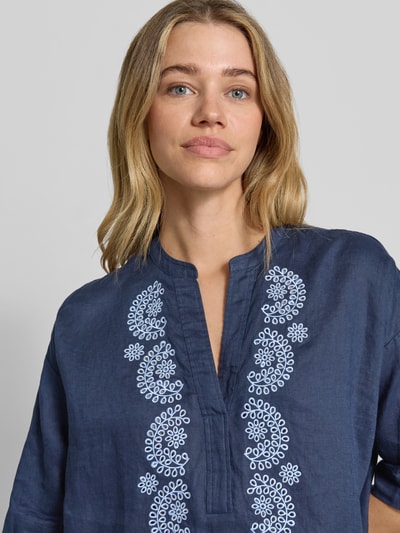 Frauenmodel trägt Leinenbluse mit 3/4-Arm und Motiv-Stitching von Emily Van den Bergh in Dunkelblau, Tunika-Kragen, Nahaufnahme Oberkörper. Loose Fit aus reinem Leinen, Stickmuster auf der Vorderseite, Damenmode.