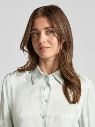 Frauenmodel trägt Bluse aus Viskose mit abgerundetem Saum von Calvin Klein Womenswear in Hellgrün mit Kentkragen und Knopfleiste, Nahaufnahme Oberkörper. Rückenlänge bei Größe S: 65 cm, Ärmellänge bei Größe S: 63 cm, Straight Fit.