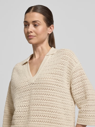 Kobiece modelka nosi sweter z dzianiny z bawełny, krój relaxed fit, kołnierzyk polo, dekolt w serek, rękaw o dł. 3/4, model 'Garakino' od OPUS, kremowy, tekstura ażurowa, zbliżenie na górną część ciała