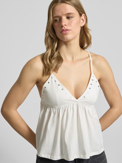 Modelka nosi Trägertop mit V-Ausschnitt und Nieten od Gina Tricot z bawełny, krój regular fit, dekolt w serek, nity, cienkie ramiączka, długość tyłu w rozmiarze S: 21 cm, zdjęcie: z przodu, zbliżenie na górną część ciała.