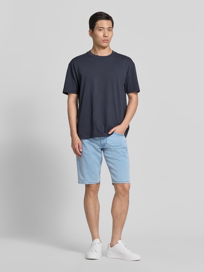 Männermodel trägt Regular Fit Jeansshorts aus Baumwoll-Mix von s.Oliver RED LABEL in hellem Denim mit 5-Pocket-Design, Ganzkörperansicht von vorne.