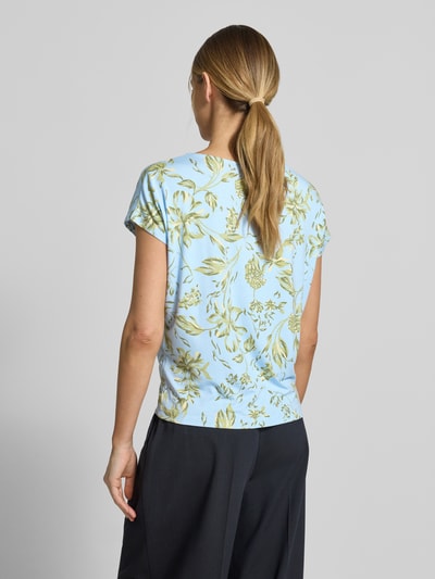 Frauenmodel trägt Relaxed Fit T-Shirt aus weichem Viskose-Mix von s.Oliver RED LABEL mit Florales-Allover-Muster in Hellblau und Grün, U-Boot-Ausschnitt, Kurzarm, Ganzkörperansicht Rückansicht.