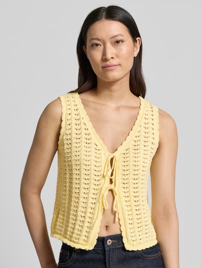 Frauenmodel trägt Strickweste mit Schnürung Modell 'DOSIA' von ICHI aus Reine Baumwolle in Regular-Fit, gelb, V-Ausschnitt, Nahaufnahme Oberkörper.