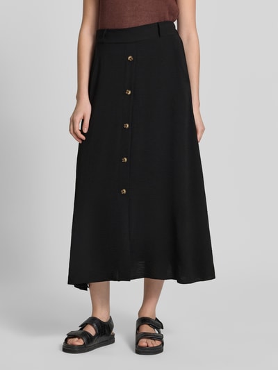 Frauenmodel trägt schwarzen Midirock mit Knopfleiste, leichte A-Linie, Gürtelschlaufen, Modell 'Cath' von Soyaconcept, Nahaufnahme Unterkörper. Bundweite Größe S: 36 cm, Gesamtlänge: 90 cm.