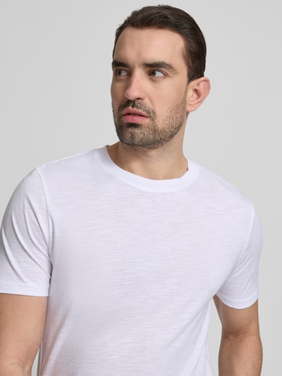 Męski model nosi Regular Fit T-Shirt mit Rundhalsausschnitt od MCNEAL z czystej bawełny, biały kolor, tekstura lekko melanżowa, krój regular fit, długość tyłu w rozmiarze M: 67 cm, zbliżenie na górną część ciała, widok z przodu.