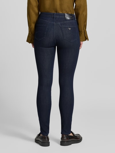 Frauenmodel trägt Slim Fit Jeans aus Viskose-Mix mit Lyocell-Anteil von Emporio Armani in Dunkelblau, 5-Pocket-Design, Ganzkörperansicht Rückansicht.