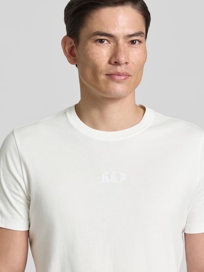 Männermodel trägt T-Shirt mit Rundhalsausschnitt und Label-Stitching von GAP in Weiß, Regular Fit, reine Baumwolle, Nahaufnahme Oberkörper.