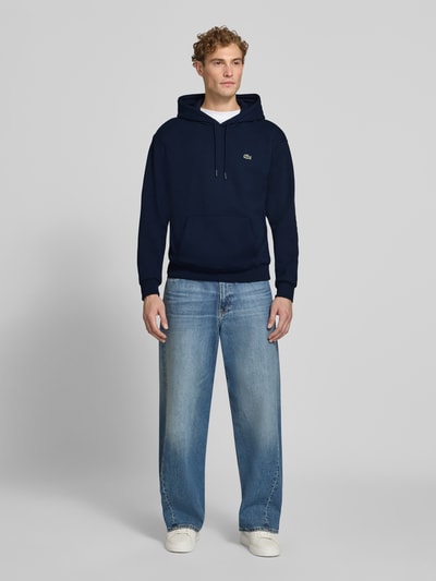 Mannelijk model draagt donkerblauwe Relaxed Fit Hoodie uit katoenmix van Lacoste, Heren sweatshirt, Ganzörperaanzicht van voren.
