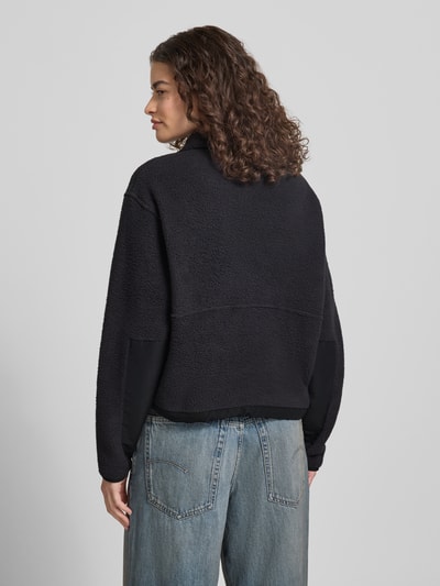 Frauenmodel trägt Fleecepullover mit Troyer-Kragen Modell 'YUMIORI' von The North Face, schwarze Farbe, Struktur-Fleece, Gerade Passform, Label-Detail, elastische Abschlüsse, Rückenlänge 54 cm, Schulterbreite 51 cm, Brustweite 56 cm, Ärmellänge 58 cm, Ganzkörperansicht Rückansicht.