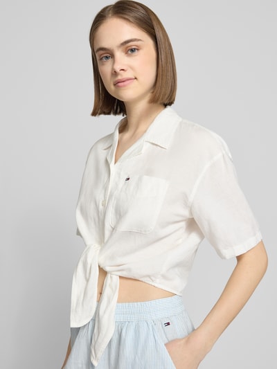 Frauenmodel trägt Regular Fit Leinenbluse aus Leinenmix mit Bindedetail von Tommy Jeans, Optik: Unifarben, Logo-Stitching, Cropped, Kurzarm, V-Ausschnitt, einreihige Knopfleiste, Leinen-Mix, Nahaufnahme Oberkörper.