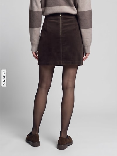 Frauenmodel trägt A-Linie Mini-Rock aus Baumwoll-Mix von Marc O’Polo DENIM in Dunkelbraun, strukturierte Oberfläche, Ganzkörperansicht Rückansicht, KI-modifiziertes Bild.