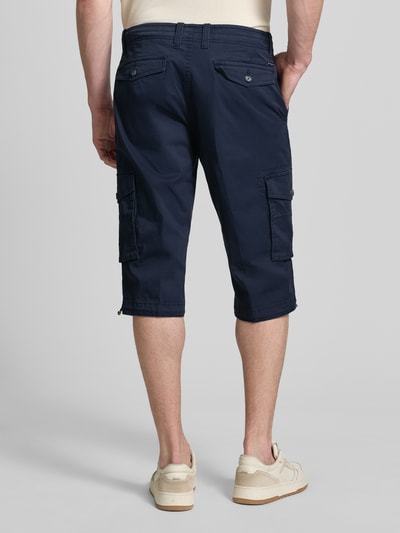 Mężczyzna nosi Capri Cargo Pants mit Pattentaschen od bugatti, bawełna z domieszką stretchu, krój straight fit, granat, widok całej sylwetki z tyłu. Szerokość w rozmiarze 50: 46 cm, długość nogawki wewnętrznej: 41 cm.