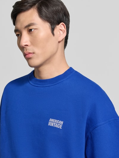 Männermodel trägt T-Shirt mit Logo Modell 'PLIZZY' von American Vintage in Blau aus Reine Baumwolle mit Rundhalsausschnitt, Nahaufnahme Oberkörper. Relaxed-Fit, Rückenlänge bei Größe S 67 cm.