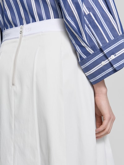 Frauenmodel trägt weißen Midirock mit Nahtreißverschluss Modell 'Vivian' von Raffaello Rossi, gelegt gefaltet, Logo-Stitching, Nahaufnahme Rückansicht.