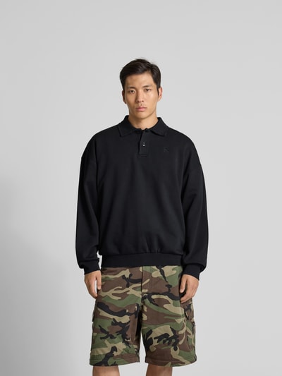Männermodel trägt schwarzes Regular Fit Poloshirt aus Baumwoll-Mix von VETEMENTS, Relaxed Fit, Polokragen, Sweat, Nahaufnahme Oberkörper.