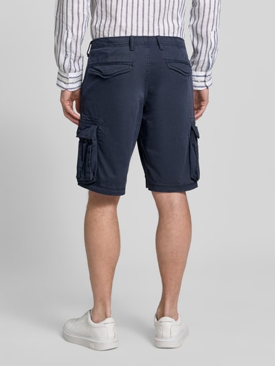 Männermodel trägt dunkelblaue Shorts mit Cargotaschen Modell 'NEW 24' von GAP aus Baumwoll-Elasthan-Mix, Ganzkörperansicht Rückansicht.