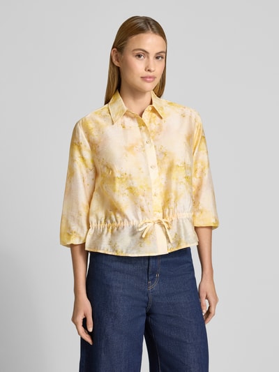 Frauenmodel trägt Regular Fit Bluse aus Lyocell-Mix mit 3/4-Arm von Jake*s Collection im Allover-Look, Hemdblusenkragen, Schnürung, Ganzkörperansicht von vorne. Rückenlänge 53 cm, Ärmellänge 45 cm, sanfte Gelbtöne, glatte Textur, Größe 36.