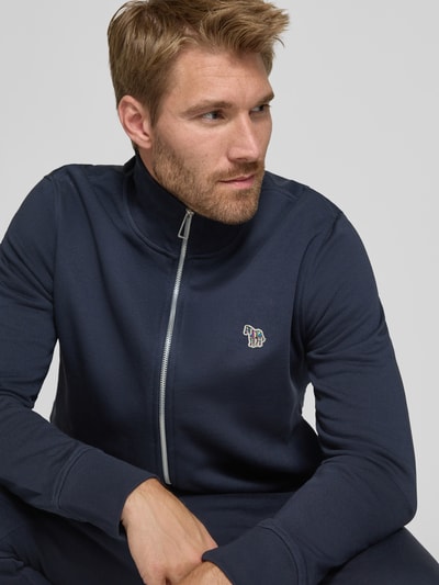 Männermodel trägt Regular Fit Sweatjacke aus Baumwolle von Paul Smith in Dunkelblau, Stehkragen, Label-Stitching, Nahaufnahme Oberkörper.