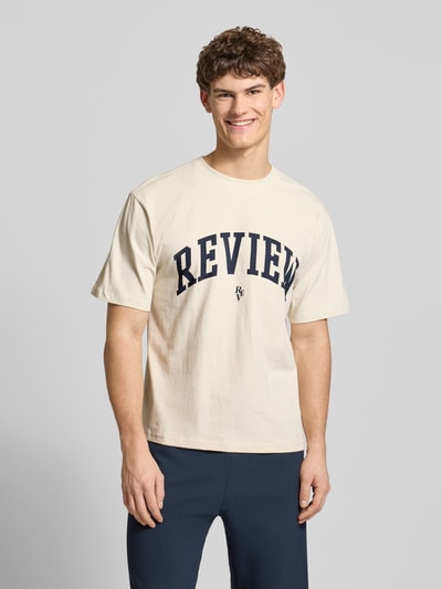 Männermodel trägt T-Shirt mit Label-Print und Rundhalsausschnitt von REVIEW, cremefarben, reine Baumwolle, Regular Fit, Ganzkörperansicht von vorne.