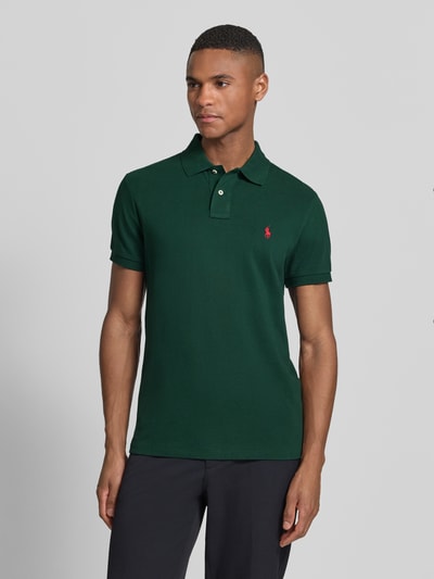 Männermodel trägt Slim Fit Poloshirt aus reiner Baumwolle von Polo Ralph Lauren, Optik: Unifarben, Polokragen, Logo-Stitching, Materialverarbeitung: Piqué, Farbe: Dunkelgrün, Kurzarm, Ärmelabschluss: Gerippt, Ganzkörperansicht von vorne.