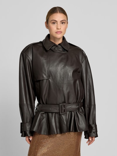 Frauenmodel trägt Oversized Jacke aus echtem Lammleder von ROTATE in Schwarz mit Umlegekragen, Gürtel, Knopfverschluss, Ganzkörperansicht von vorne; Rückenlänge bei Größe 36: 76 cm, Brustweite: 67 cm, Ärmellänge: 67 cm.