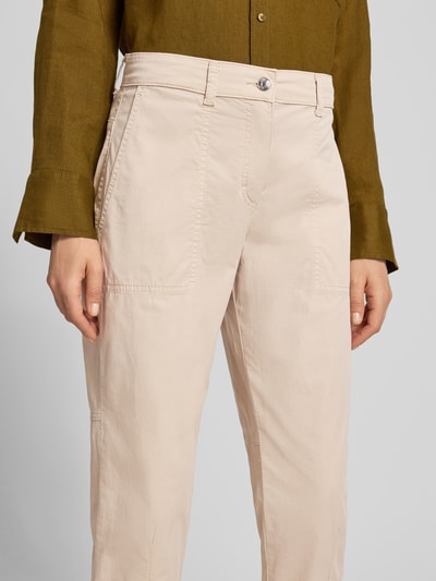 Frauenmodel trägt Hose in verkürzter Passform Modell 'EBBY' von MAC aus Baumwoll-Elasthan-Mix in Beige mit Eingrifftaschen, Nahaufnahme Oberkörper.