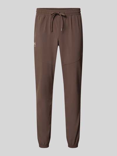 Produktfoto, Relaxed Fit Trainingshose mit Label-Print von Under Armour in Braun, glatte Stoffstruktur, elastischer Bund, Kontrastlogo vorn, Herren Trainingshose von Under Armour