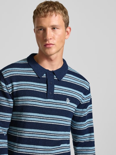 Männermodel trägt Strickpullover mit Polokragen in Bouclé-Optik von Review, Streifenmuster, Label-Stitching, Nahaufnahme Oberkörper.