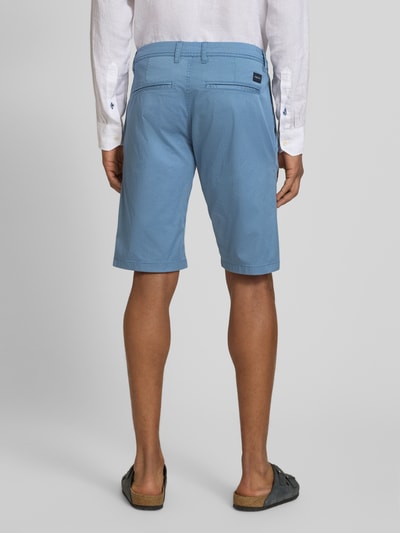 Männermodel trägt Slim Fit Chinoshorts aus Baumwoll-Mix von Tom Tailor, efekt: wzór na całej powierzchni, krój slim fit, aplikacja z logo, szlufki na pasek, zapięcie na guzik i ukryty zamek błyskawiczny, wpuszczane kieszenie, kieszenie z tyłu, wykończenie materiału: splot twill, materiał: mieszanka bawełny, całość w odcieniach niebieskiego, tkana faktura, Ganzkörperansicht Rückansicht.