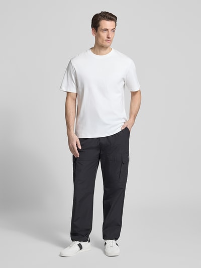 Männermodel trägt Relaxed Fit T-Shirt mit Rundhalsausschnitt von Antony Morato in Weiß, reine Baumwolle, schwarze Hose, Ganzkörperansicht von vorne.
