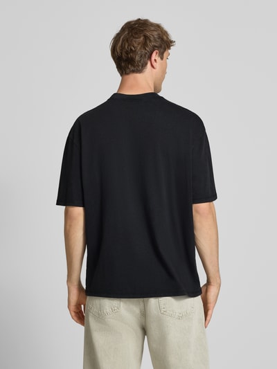 Mężczyzna nosi Oversized T-Shirt mit Label-Stitching von Pegador, czarny kolor, bawełna, krój oversize, okrągły dekolt, długość tyłu M: 70 cm, całopostaciowy widok z tyłu.