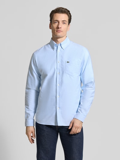 Męski model nosi Regular Fit Freizeithemd aus reiner Baumwolle od Lacoste, jasnoniebieska bawełna, guziki, kieszeń, widok z przodu, krój regular fit