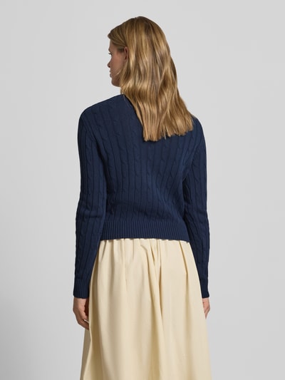 Frauenmodel trägt Strickpullover mit Zopfmuster und Label-Stitching von REVIEW in Dunkelblau, aus Baumwoll-Mix, Regular-Fit, Rückenlänge 52 cm, Ärmellänge 69 cm, Ganzkörperansicht Rückansicht.