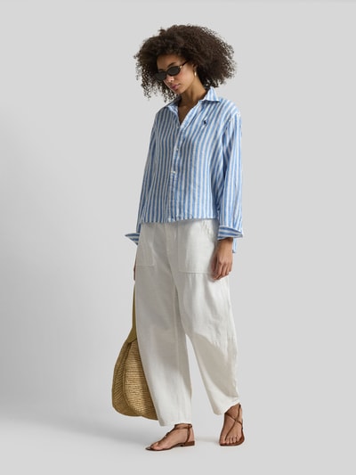 Frauenmodel trägt Boxy Fit Hemdbluse aus reinem Leinen von Polo Ralph Lauren mit blau-weißem Streifenmuster und Logo-Stitching, Ganzkörperansicht von vorne.