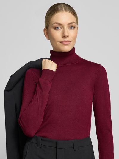 Frauenmodel trägt Slim Fit Strickpullover aus Viskose-Mix Modell 'IHLULS' von ICHI, dunkles Rot, glatte Struktur, Nahaufnahme Oberkörper. Damen Strickpullover, Rollkragen und elastische Abschlüsse sind sichtbar, Rückenlänge Größe S ca. 61 cm, Ärmellänge ca. 66 cm.