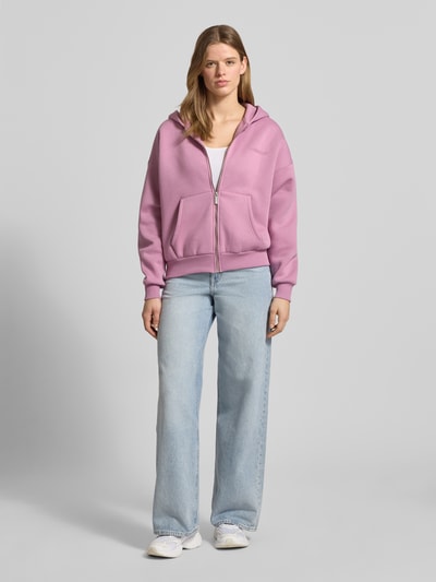 Frauenmodel trägt Sweatjacke mit Logo und Känguru-Tasche von Review aus Baumwoll-Mix, Relaxed-Fit, Kapuze, Reißverschluss, Ganzkörperansicht von vorne.
