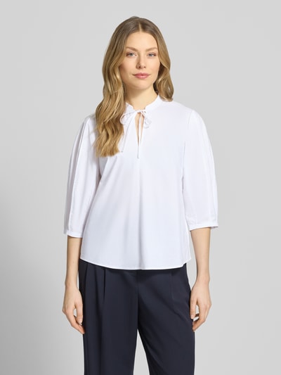 Kobiece model prezentuje Bluse mit Serafino-Ausschnitt und Keulenarm von Christian Berg Woman Selection, biała bawełna, luźny krój, rękaw 3/4, zaokrąglony dół, widok na cały przód.