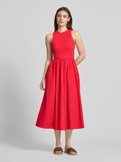 Frauenmodel trägt Midikleid aus reiner Baumwolle von Tommy Jeans in Rot, Optik: Unifarben, Passform: A-Linie, Länge: Midi, Rundhals-Ausschnitt, Ärmelform: Ohne, Ganzkörperansicht von vorne.