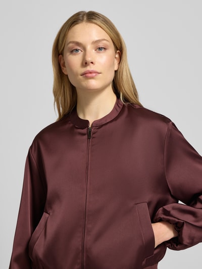 Modelka kobieca nosi Blouson mit Reißverschluss Modell 'Jupita' od OPUS, kolor bordowy, gładka tekstura, stójka, z kieszeniami, zapięcie na zamek, proste linie, widok z przodu, zbliżenie na górną część ciała.