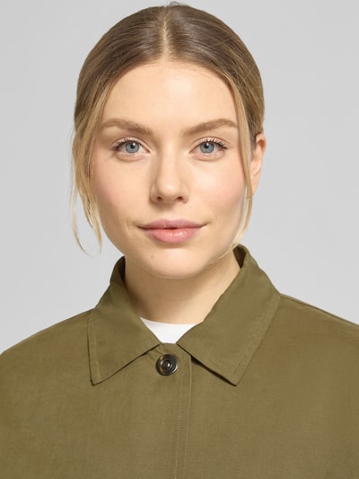 Frauenmodel trägt Blouson aus reiner Baumwolle von WHITE LABEL in Oliv mit Umlegekragen und durchgehender Knopfleiste, Nahaufnahme Oberkörper. Lockere Passform, Eingrifftaschen, Rückenlänge 62 cm, Schulterbreite 40 cm, Brustweite 64 cm, Ärmellänge 65 cm.