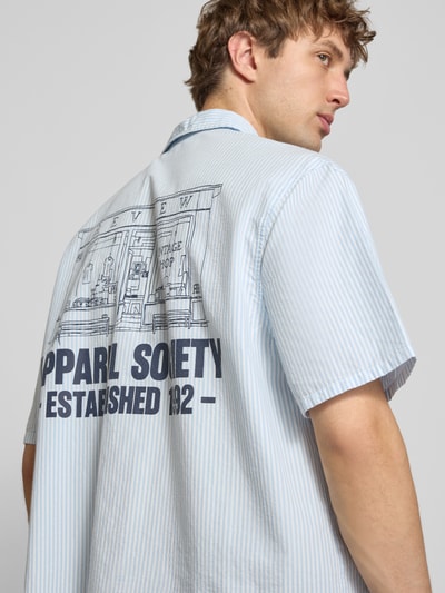 Männermodel trägt Regular Fit Freizeithemd mit 1/2-Arm von REVIEW, leichte Baumwolle, blaue Streifen, gedrucktes Label-Detail, Ganzkörperansicht Rückansicht.
