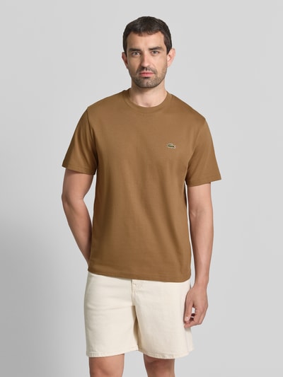Männermodel trägt Relaxed Fit T-Shirt aus reiner Baumwolle Modell 'BASIC ON' von Lacoste in Braun, glatte Oberfläche, Ganzkörperansicht von vorne, Herren T-Shirt von Lacoste.