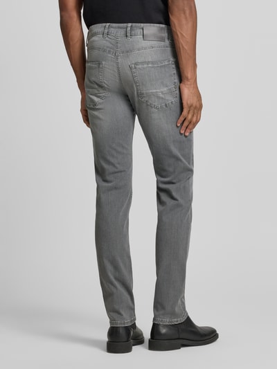 Männermodel trägt Regular Fit Jeans aus Baumwoll-Mix Modell 'Arne Pipe' von MAC in Grau mit 5-Pocket-Design, Label-Patch, Ganzkörperansicht Rückansicht.