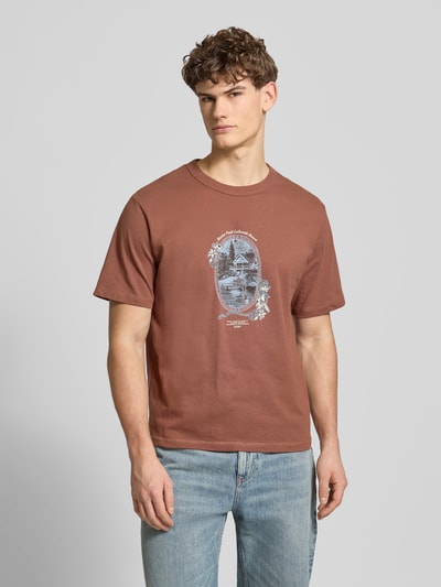 Mannenmodel draagt T-shirt met Label-Print Modell 'NIAGARA' van Jack & Jones in bruin, rechte fit, ronde hals, opdruk voorzijde, katoen, voorkant volledige lichaamsweergave.