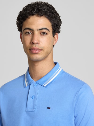 Männermodel trägt Regular Fit Poloshirt aus reiner Baumwolle von Tommy Jeans, Optik: Unifarben, Logo-Stitching, Nahaufnahme Oberkörper.