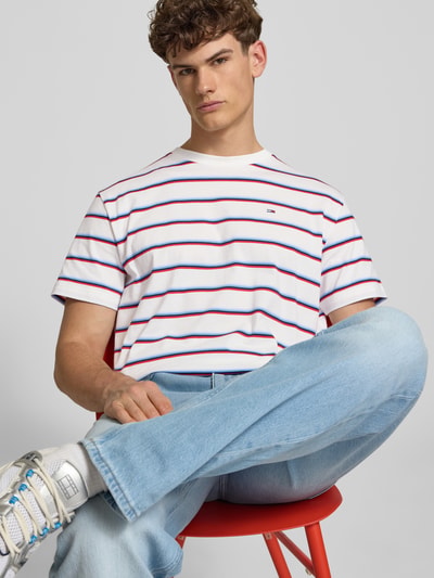Männermodel trägt Regular Fit T-Shirt aus reiner Baumwolle von Tommy Jeans mit Optik:Allover-Muster, gestreift, Logo-Stitching, Rundhals, Kurzarm, Materialverarbeitung: Jersey, Ganzkörperansicht von vorne.