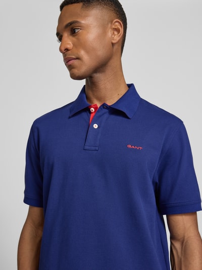 Männermodel trägt Regular Fit Poloshirt mit Logo-Stitching von Gant, Baumwoll-Mix, Polokragen, kurzärmelig, Nahaufnahme Oberkörper.