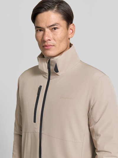 Męski model nosi Regular Fit Jacke mit Logo-Print od Lindbergh, elastyczna mieszanka materiałów, beżowa, napoleońska kieszeń, nadruk z logo, rozmiar M, zbliżenie na górną część ciała